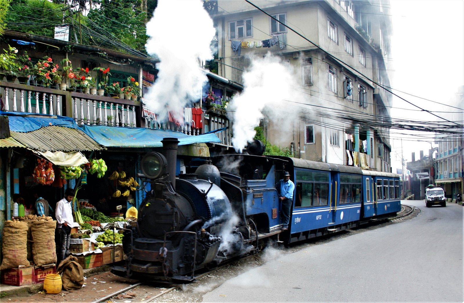 A premium outstation cab driving alongside the tracks of the Darjeeling Himalayan Railway en route from NJP